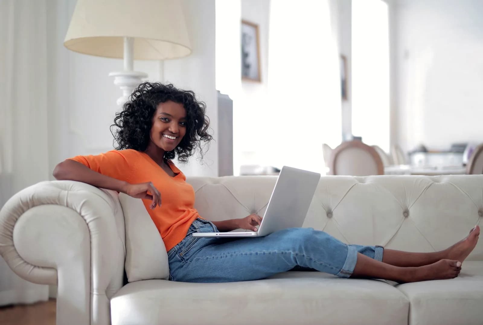 Woman smiling on a sofa while setting up an account on her laptop