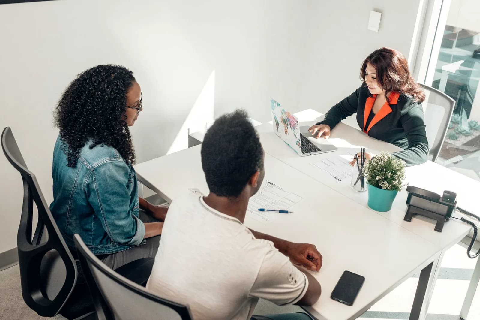 A small team collaborating around a laptop in a bright office